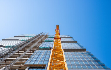 Wall Mural - Looking up to a high-rise building with a yellow crane and an Elevator on Construction Site 