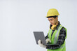 © Kanyanat - The engineer wears light green protective clothing. wearing a yellow hat wearing white gloves yellow headphones turn to the side standing working on laptop on white background