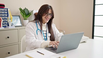 Wall Mural - Young beautiful hispanic woman doctor using laptop working at clinic