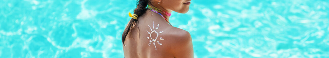 Poster - A child on the beach puts sunscreen on his back. Selective focus.