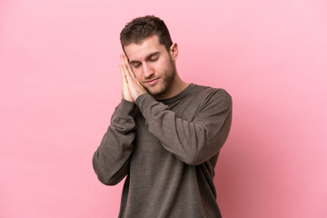 Poster - Young caucasian man isolated on pink background making sleep gesture in dorable expression