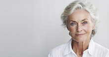 Portrait Of Beautiful Senior Woman With Grey Hair And Blue Eyes In Front Of White Background.