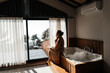 Woman is sitting on bathtub with scrub in hands.