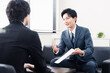 © maroke - 商談で書類を提示するビジネスマン