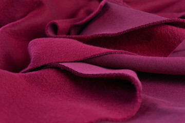A piece of fabric lies in beautiful waves. layers of French terry pink amaranth textile.