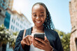 © Daniels C/peopleimages.com - Phone, walking and a business black woman in the city, searching for directions or typing a message. Mobile, smile and gps with a young female employee looking for a location on a navigation app