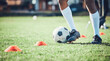 © Daniels C/peopleimages.com - Soccer player, feet and ball with training cone on a field for sports game and fitness. Legs or shoes of male football or athlete person outdoor for agility exercise, performance or workout on grass