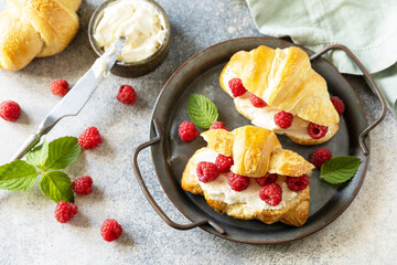 Canvas Print - Healthy food dessert concept, french pastry. Tasty freshly baked croissants with cream cheese and raspberry on a stone background.