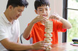 Asian father and son playing wood blocks game Carefree kid playing wood blocks game building constructor from blocks with father at home