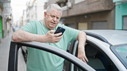 Poster - Middle age grey-haired man using smartphone standing by car at street