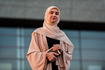 Wall Mural - Portrait of a Muslim business woman in hijab near the office building.