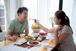Happiness asian family with husband and wife eating dining food together in the kitchen at home, happy couple eating lunch with enjoy, dating and honeymoon, lifestyles and nutrition concept.