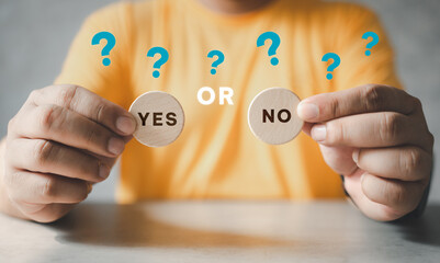 Man holding two wooden blocks with yes or no written on them, making the decision concept. Yes or No choice. Decision making and choosing between right and wrong.