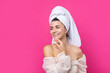 Portrait of young beautiful woman after bath. Beauty face of a cheerful attractive girl with towel on head against a pink background.