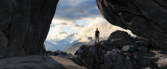 Wall Mural - adventurous man standing in cave on top of mountain. extreme adventure composite