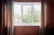 Closed plastic window and wall inside the room. Window with view of summer sunny backyard of wooden country house.