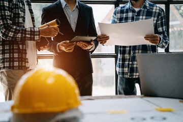 Wall Mural - Engineer teams meeting working together wear worker helmets hardhat on construction site in modern city.Asian industry professional team.