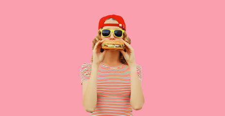 Wall Mural - Portrait of stylish smiling young woman with burger fast food on pink background