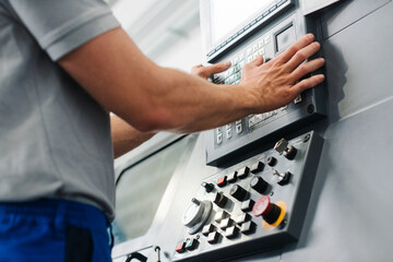 manufacturing worker programming industrial cnc machine tool while entering work data