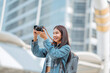 © oatawa - Happy young tourist asian woman holding a mirrorless camera on street in the city, Tourist journey trip concept.