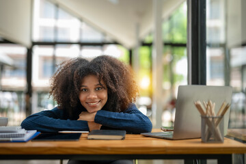 Portrait of smiling young black woman taking Break from work. Resting on the table.