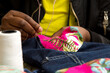 Costureira costurando tecido colorido em jeans a mão com linha e agulha. Descarte da Indústria Têxtil de São Paulo, Brasil. 