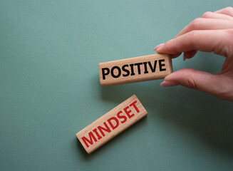 Positive Mindset symbol. Concept words Positive Mindset on wooden blocks. Businessman hand. Beautiful grey green background. Business and Positive Mindset concept. Copy space.