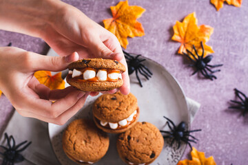 Close-up gingerbread cookies with marshmallow teeth in children's hands for halloween top view