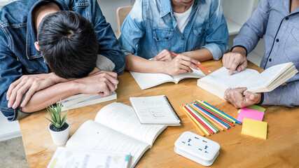 Wall Mural - high school or college student group sitting at desk in library studying and reading, doing homework