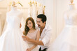 © kanpisut - Bride and groom choosing wedding dress in shop. Bride and groom choose dress and try to fitting in modern wedding studio.