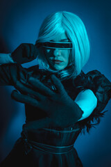 Portrait of cosplay woman in black costume and a white wig in studio with blue led light