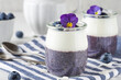 Healthy vegan breakfast of blueberry yogurt parfaits made with fresh berries, coconut yoghurt, chia pudding and edible flowers
