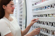 Beautiful young woman choosing eyeglasses frame in an optical store.