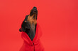 Portrait of a dachshund dog in a bright red hoodie howls at the moon with his muzzle up, funny peeping with his eye. The image of a narcissist, an egoist star with inflated self-esteem posing on stage