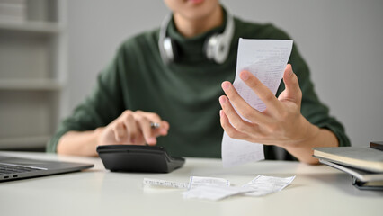 Close-up image of a male freelancer calculating his bills with a calculator