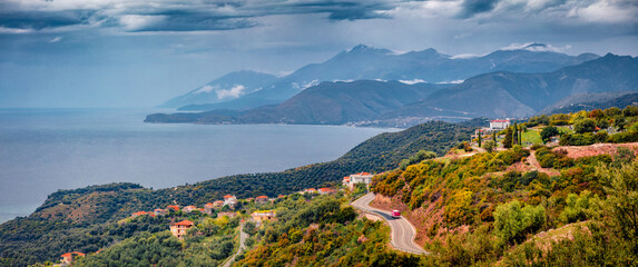 Wall Mural - Panorama of typical Albanian countryside. Dramatic landscape of Adriatic shore with asphalt road and misty mountains. Majestic spring morning in Albania, Europe. Traveling concept background.