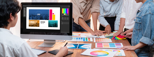 Poster - Graphic designer work on computer laptop and with graphic drawing pen while brainstorming unique design with professional graphic team in modern digital studio workplace. Panorama shot. Scrutinize