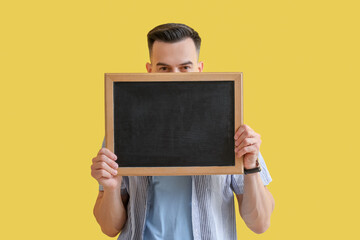 Canvas Print - Male teacher with chalkboard on yellow background