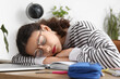 Tired female student sleeping after doing lessons at home