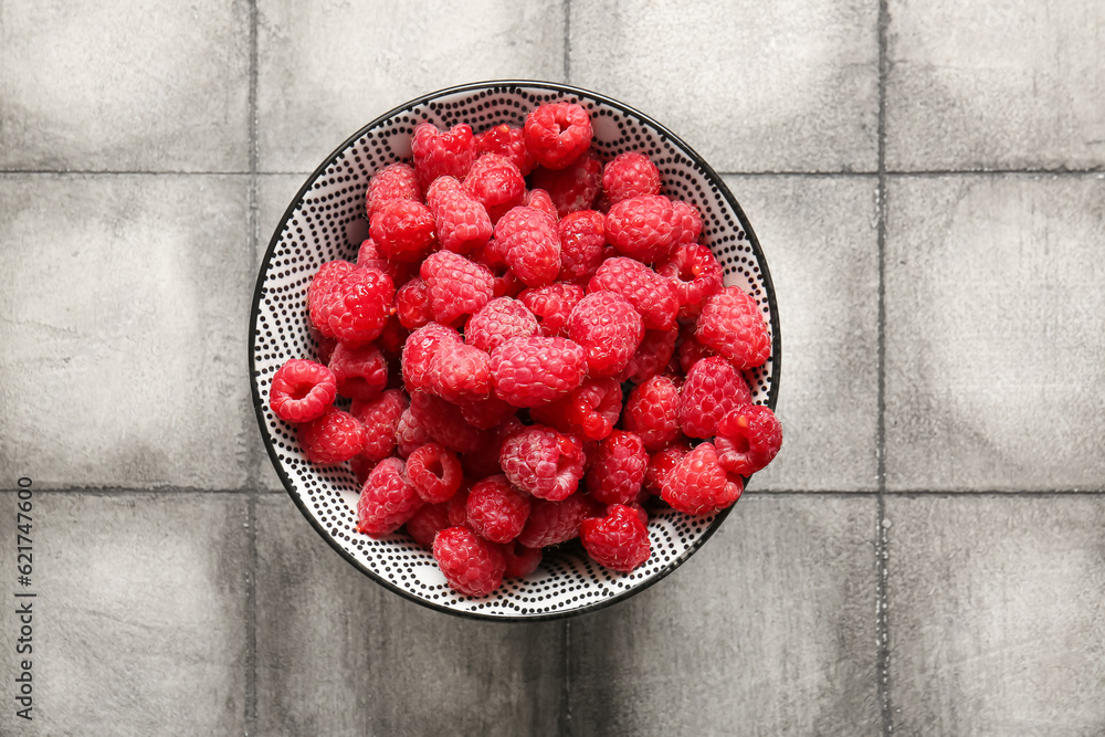 Bowl with fresh raspberries on grey tile table