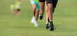 Running children, young athletes run in a kids run race, running on grass detail on legs, running in the light of morning