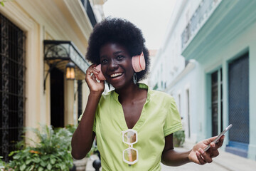 afro american woman with headphones dancing on the street, young caribbean girl in Latin America