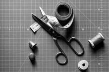 Close-up Of Sewing Tools: Measuring Tape, Scissors, And Thimble With Cutting Mat In The Background. View From Above.