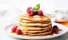 pancakes with raspberries in white plate, raspberries on top of pan cakes with honey