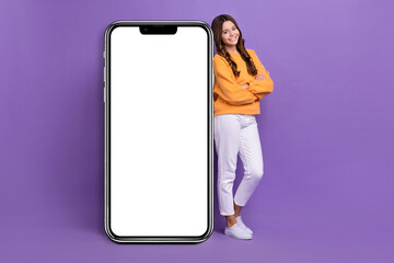 Sticker - Full size photo of positive nice girl crossed arms presenting huge empty space telephone screen isolated on violet color background