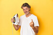 © Asier - Man with iron in hand on a yellow background pointing with finger at you as if inviting come closer.