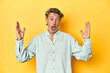 © Asier - Middle-aged man posing on a yellow backdrop celebrating a victory or success, he is surprised and shocked.
