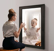 Creative conceptual collage. Excited young girl looking in mirror and seeing reflection of little girl, her child self. Concept of present, past and future, age, lifestyle, memories, generation, ad