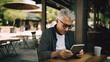 © PaulShlykov - Portrait of modern senior man reading news using ebook in outdoor cafe. Digital ink technology