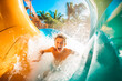 Excited man having fun on water slide in amusement park. Generative AI